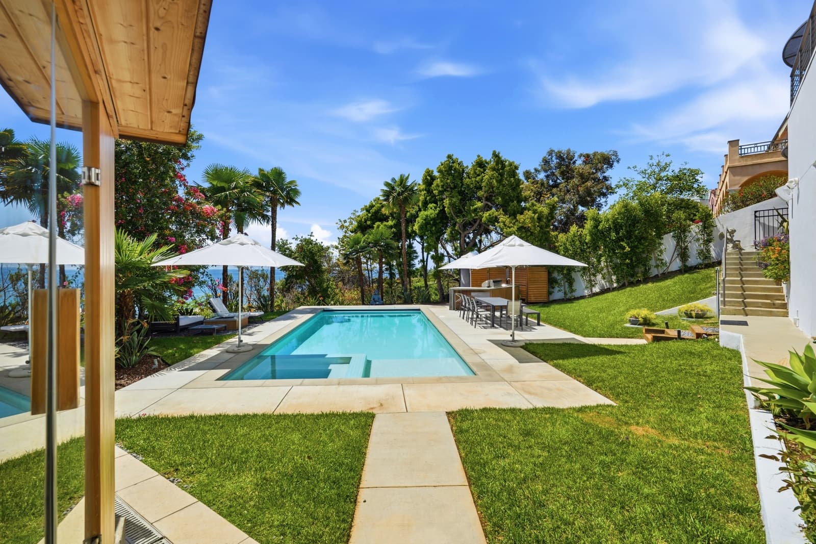 Pool terrace with palm trees and an ocean glimpse in Malibu